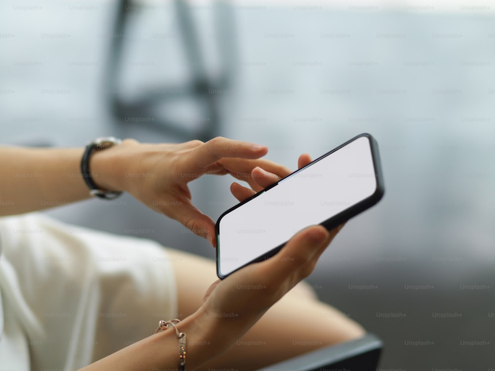 Side view of female hand holding mock-up smartphone in blurred background, clipping path