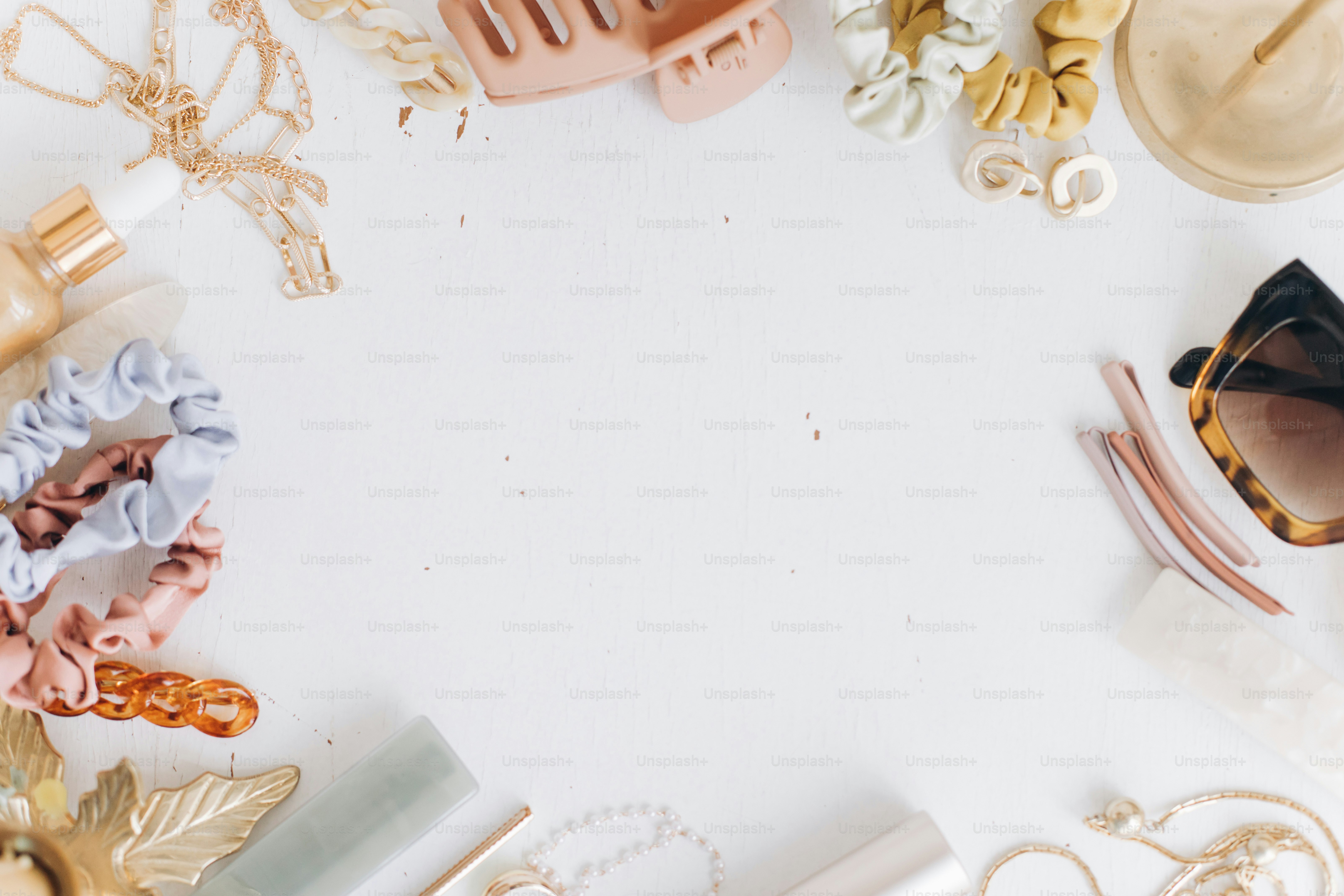 Modern summer accessories flat lay with space for text. Feminine essentials. Gold jewellery, sunglasses, hair clips, barrettes, hair bands, cosmetics on white table with vintage candles. Boho