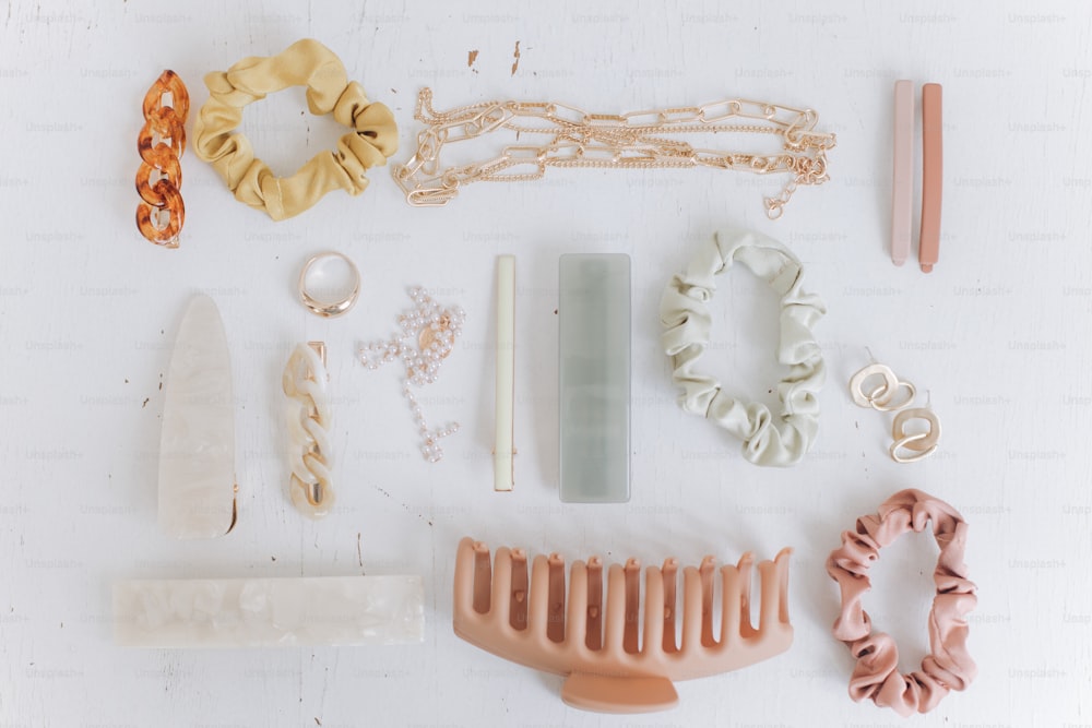 Modern summer accessories layout. Golden jewellery, hair clips and hairbands, barrettes on white table top view. Feminine essentials. Boho colorful accessories