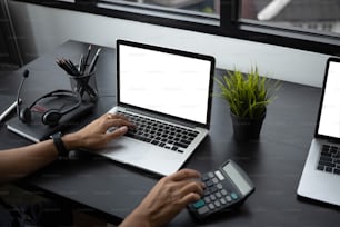 Close up view of female accountant using calculator and  working with computer laptop at modern office.