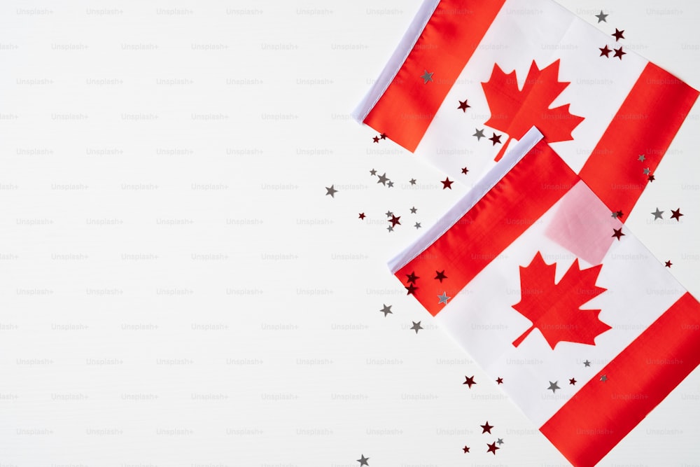 ハッピーカナダデーのバナーデザイン。白い背景にカナダの国旗と紙吹雪。フラットレイ、上面図、コピースペース。