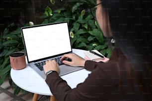Over shoulder view of businesswoman working with computer laptop at outdoor.
