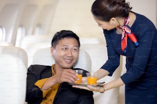 Passenger have orange juice served by an air hostess in airplane, Flight attendants serve on board