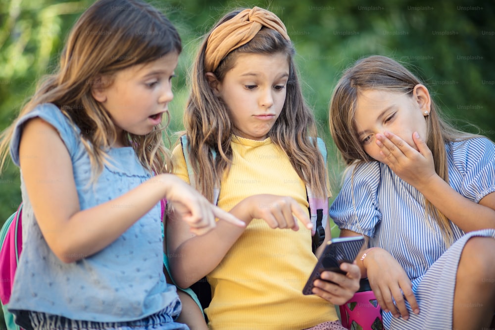 Schockierendes Video. Drei kleine Mädchen mit Smartphone.