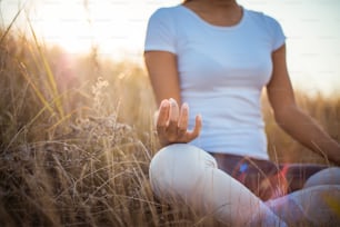 African young woman in nature sitting in yoga position. Focus is on hand.