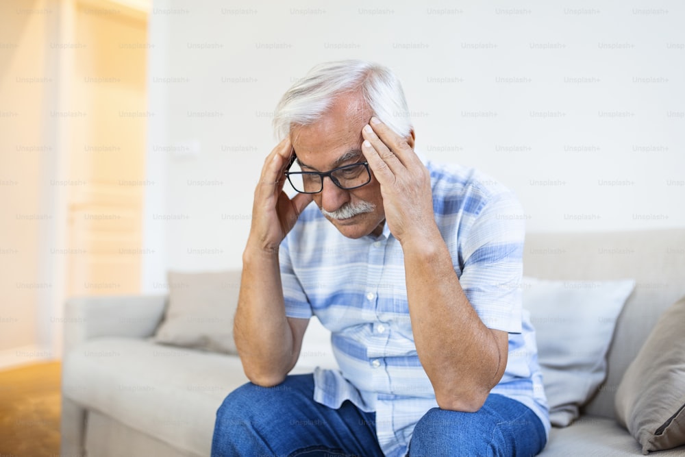 モンスター片頭痛の攻撃。不幸な引退した老人は、苦痛の表情を浮かべて頭を抱えています。頭痛に苦しむ老人の顔