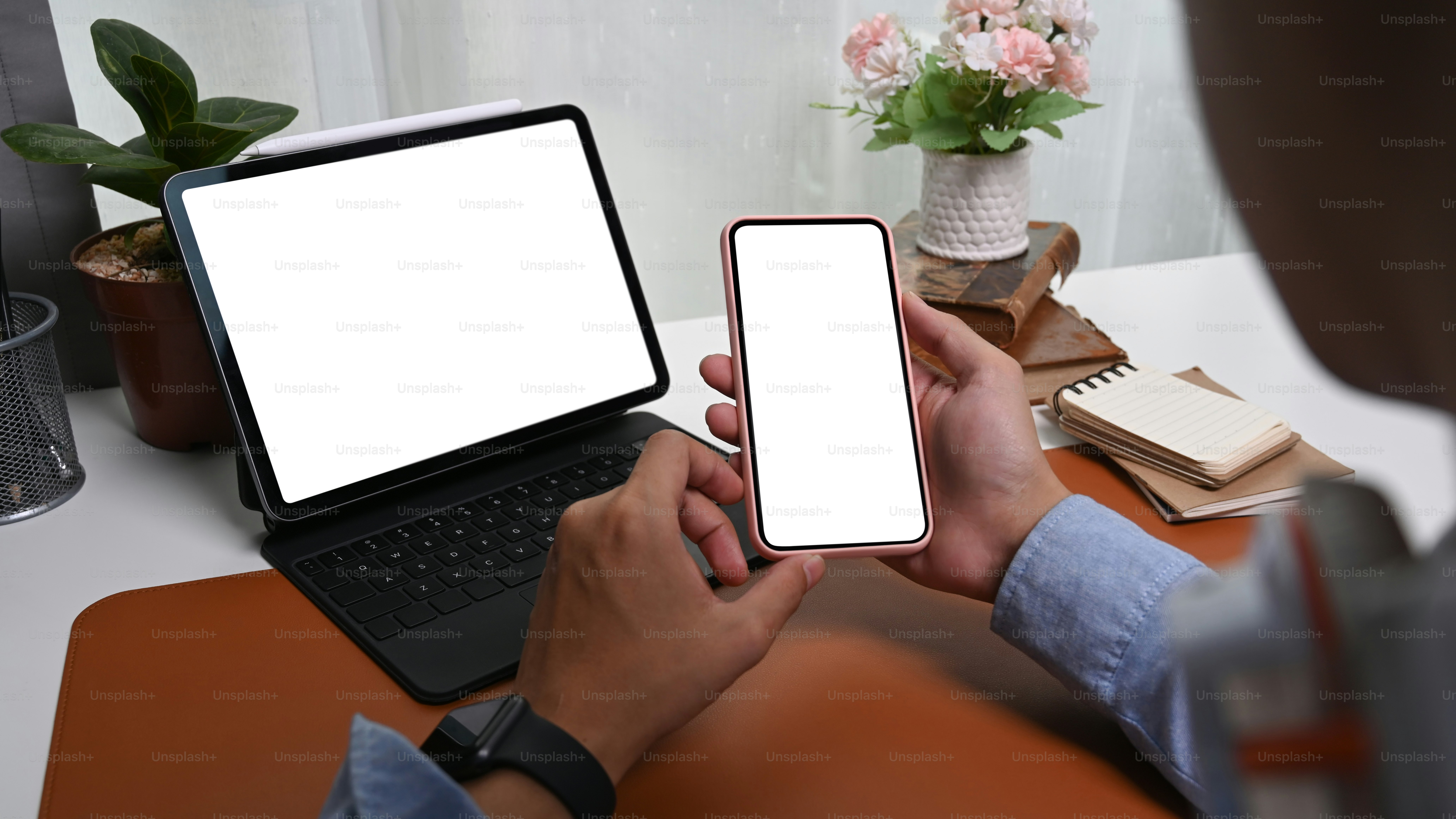 Primo piano sopra la spalla vista dell'uomo d'affari seduto davanti al tablet del computer e usando il telefono cellulare.