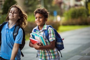 Happy boys with backpack going to home together. Focus is on background.