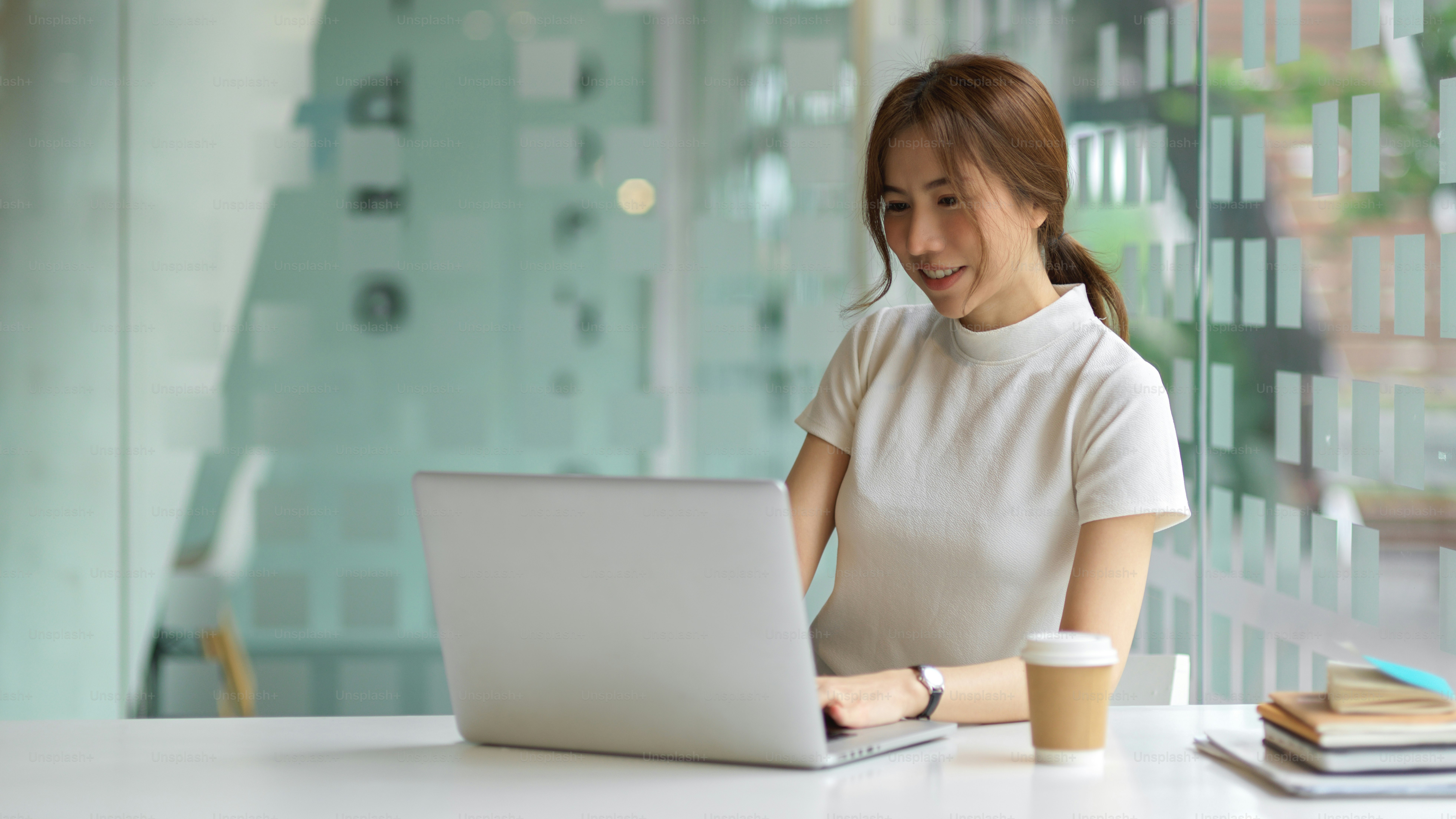 Portrait of happy young female using computer laptop on the table in co-working space