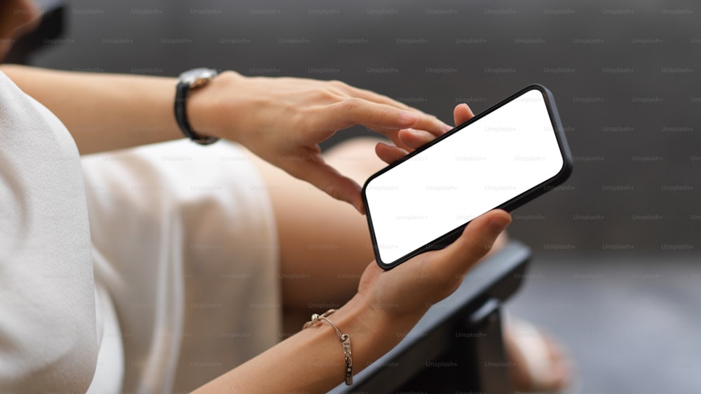 Top view of female using smartphone include clipping path screen in her hands while sitting on the armchair