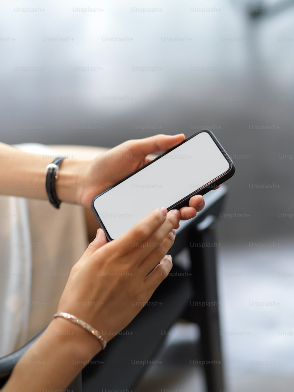 Cropped shot of female hands using smartphone include clipping path screen while sitting on the armchair