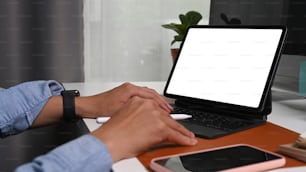 Close up view of businessman holding stylus pen and working with computer tablet at office desk.
