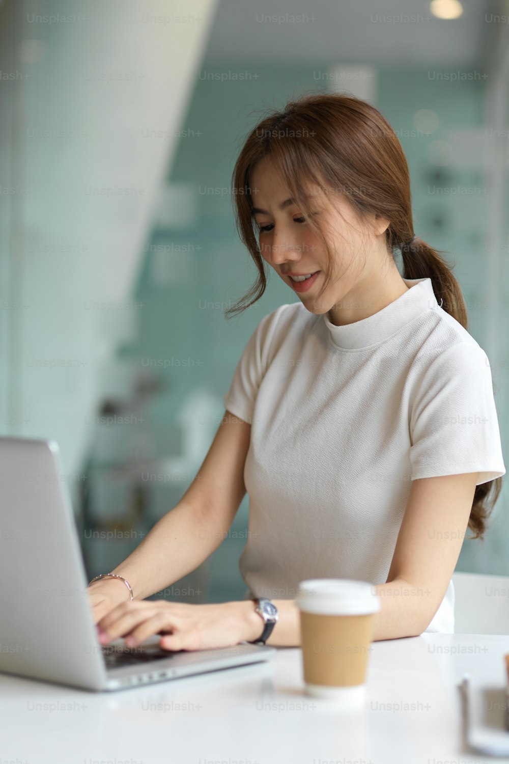 Ausschnittaufnahme einer jungen Frau mit Computer-Laptop auf dem Tisch im Coworking-Space