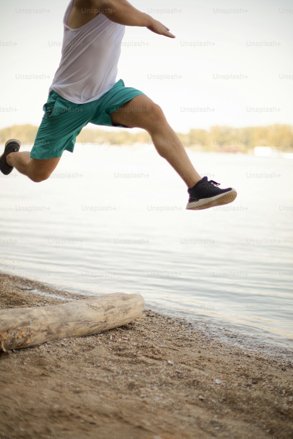 Sports man jumping and having training on the beach.