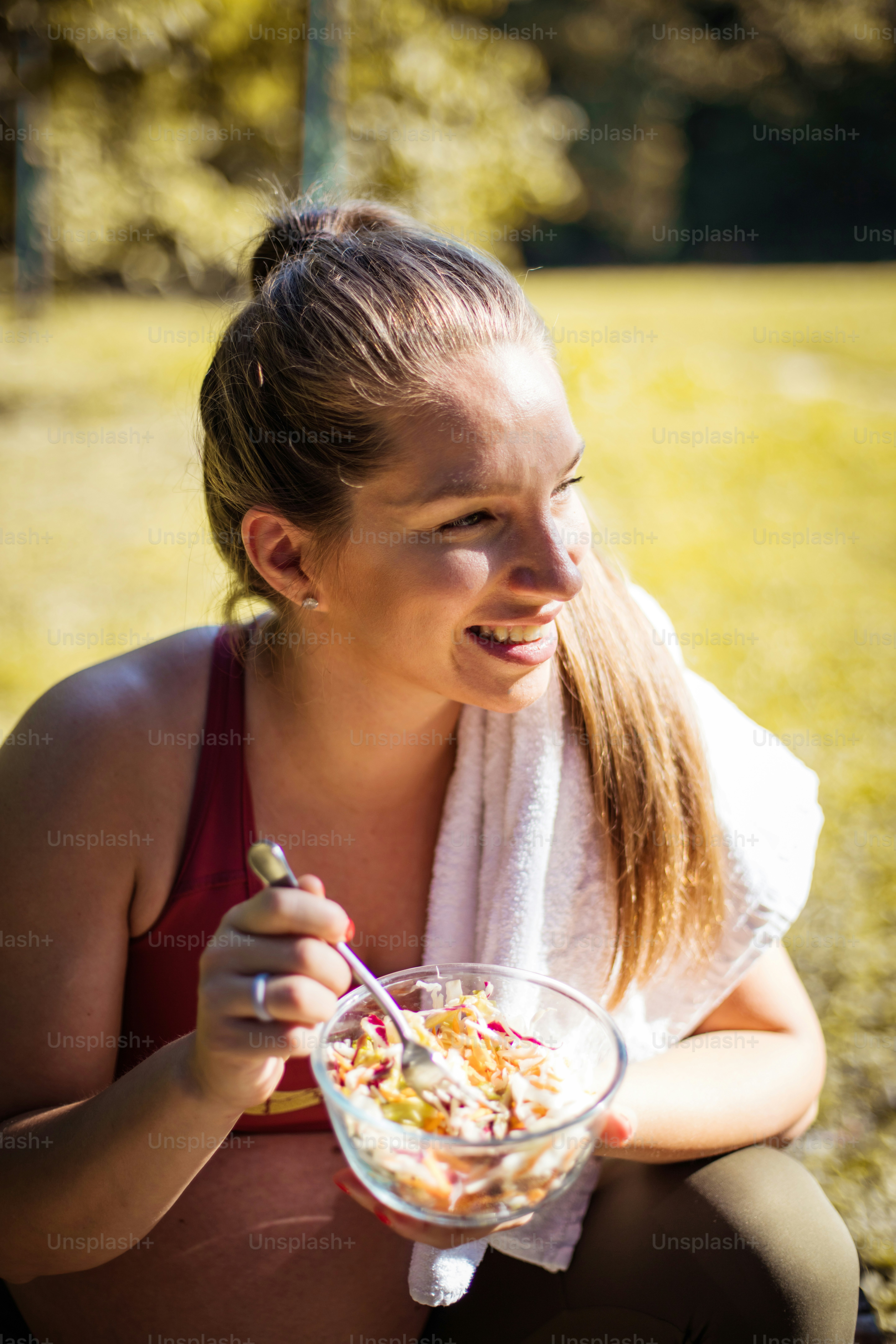 Femme enceinte mangeant de la salade après avoir fait de l’exercice dans le parc.
