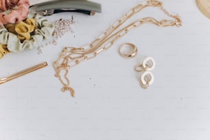 Modern golden jewellery, hair clips, barrettes on white table. Stylish gold ring, chain necklace, earrings, hairbands. Summer Boho accessories