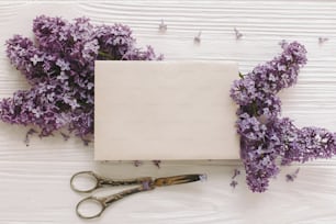 Happy mothers day. Stylish card on beautiful lilac flowers and vintage scissors, pencil on white rustic wood, top view. Happy womens day. Floral greeting card template, space for text