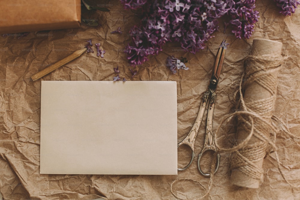 Happy mothers day. Stylish card, beautiful lilac flowers, vintage scissors, pencil and twine on rustic background, top view. Rural still life. Greeting card template, space for text