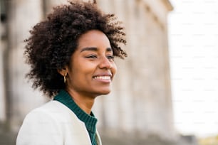 Close up of afro business woman smiling while standing outdoors on the street. Business and urban concept.