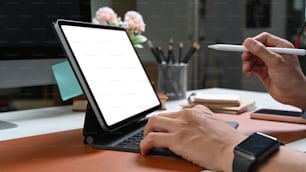 Gros plan sur les mains d’un homme d’affaires avec une montre intelligente tenant un stylet et travaillant sur une tablette d’ordinateur.