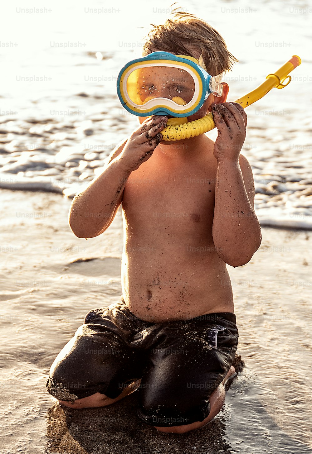 夏休みに水で楽しんでいるシュノーケリングマスクの休暇の小さな男の子。
