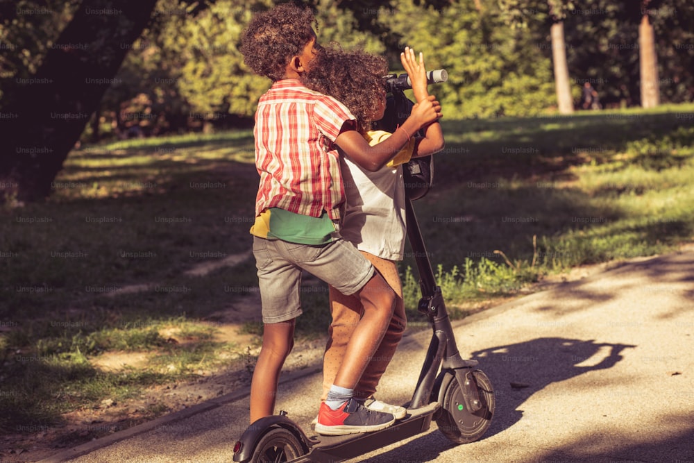 アフリカ系アメリカ人の兄妹は、電動スクーターを運転する自然界にあります。