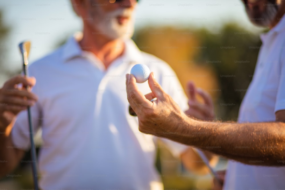 Des amis plus âgés sur le terrain de golf parlent.  La concentration est à portée de main.
