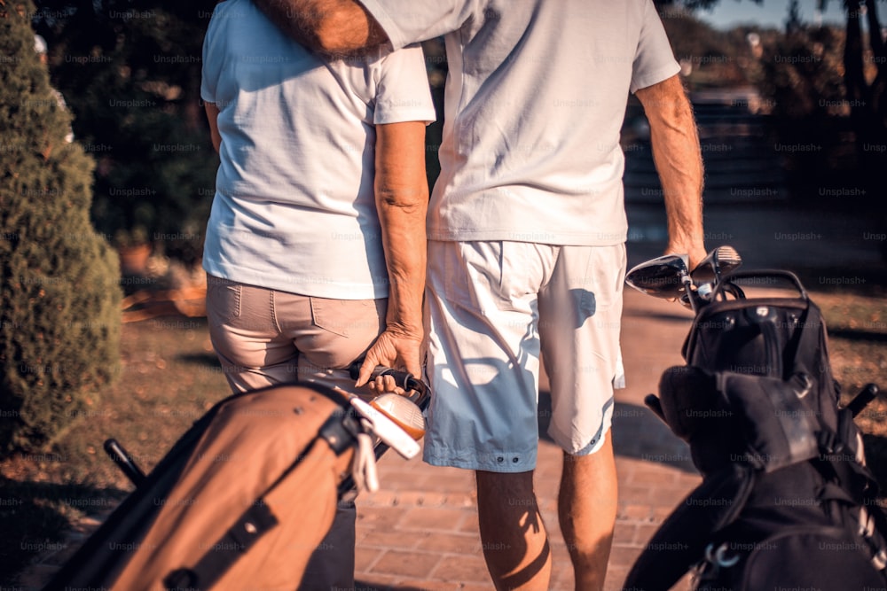 Golfistas mayores en campo de golf en abrazo. De cerca.