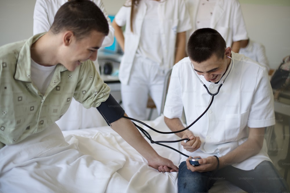 Medicine is fun.  Young student in hospital measures the patient's pressure.