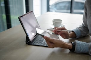 Close up view of businessman holding mobile phone and siting with computer tablet at workplace.