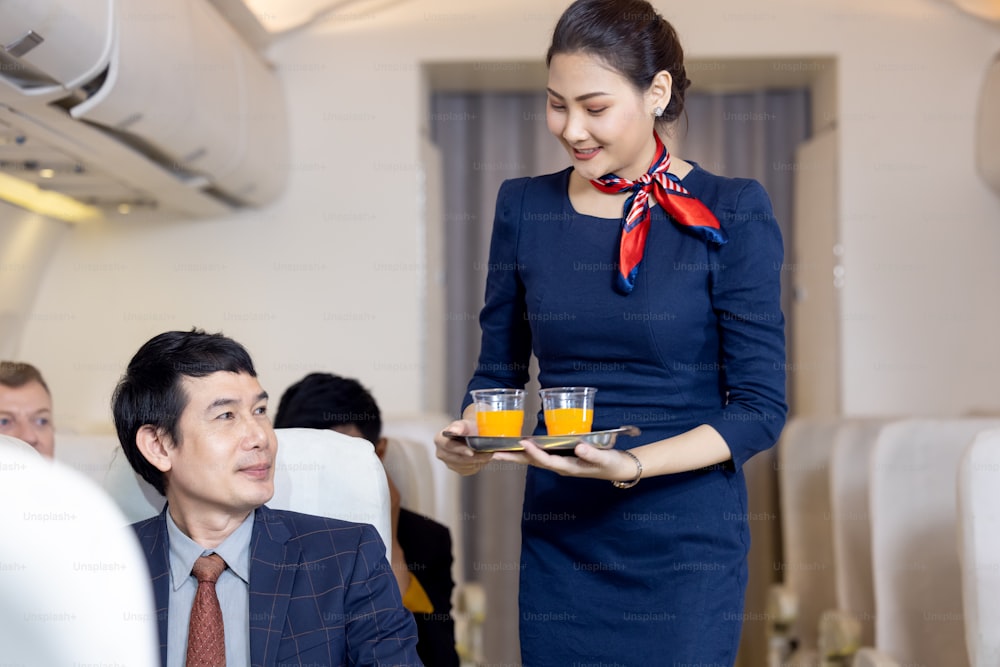 승객은 비행기에서 항공 여주인이 제공하는 오렌지 주스를 가지고 있으며, 승무원은 기내에서 봉사합니다.