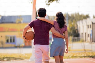 Couple walking with ball on basketball court.