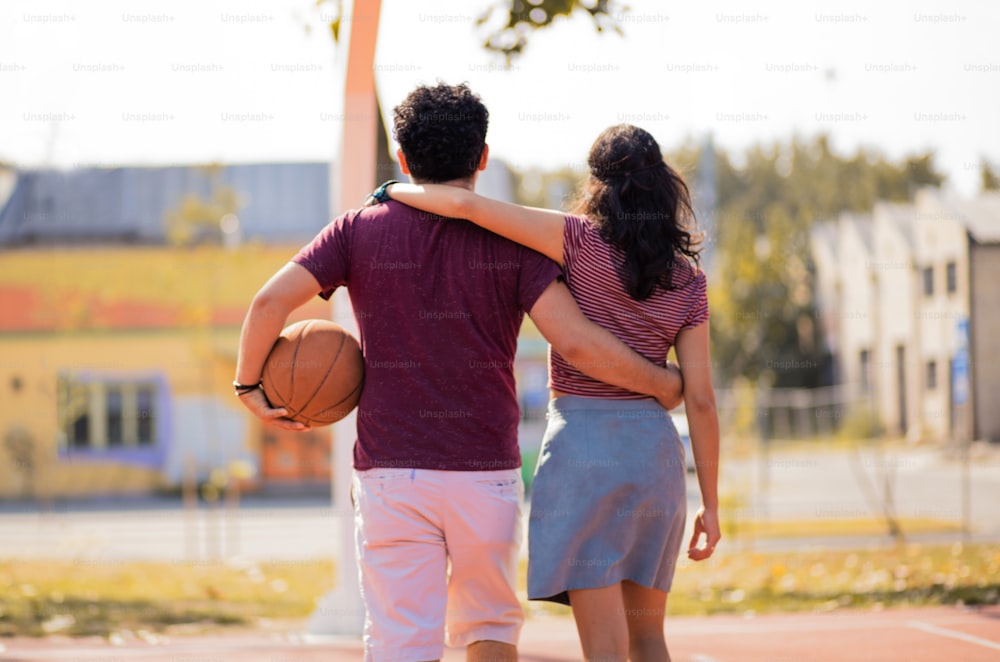 Couple walking with ball on basketball court.