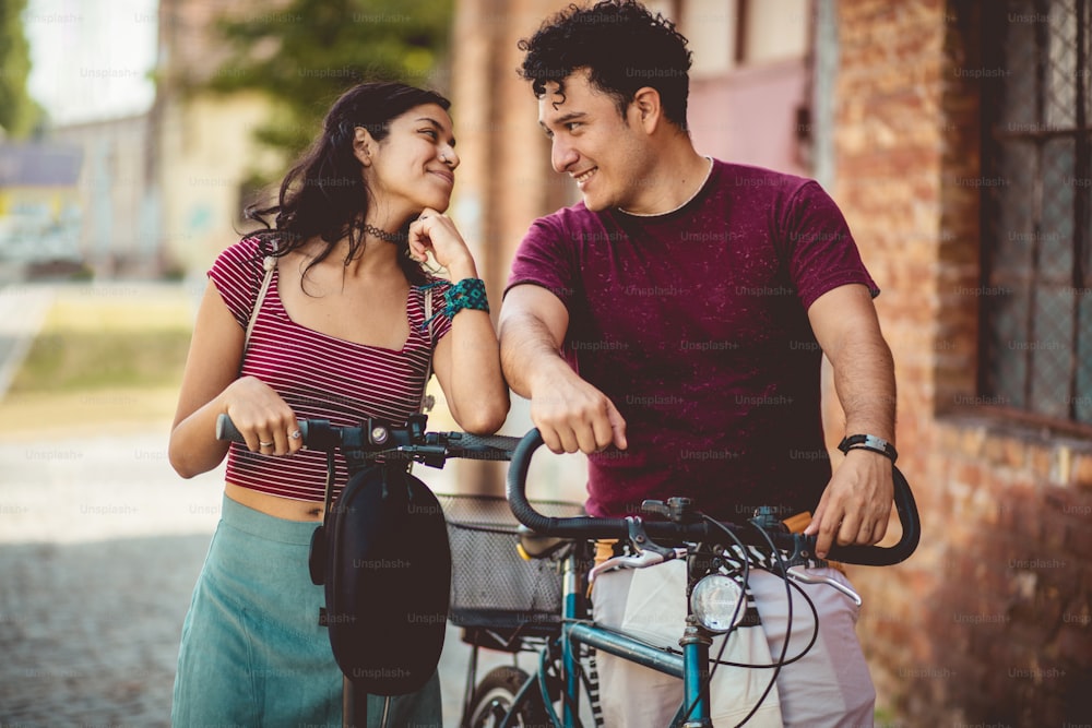 자전거와 전기 스쿠터를 탄 거리에 있는 젊은 커플.