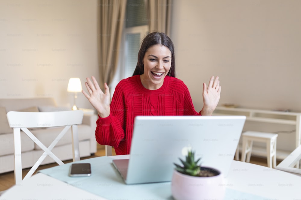 Young woman waving at laptop and talking to her friends via video call, girl student talking by video conference call, female teacher trainer tutoring by webcam, online training, e-coaching concept