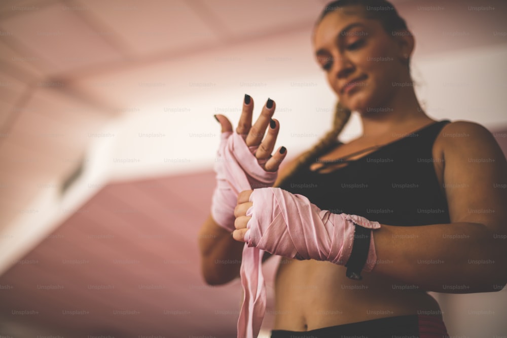 Woman putting glove for boxing. Woman in gym.