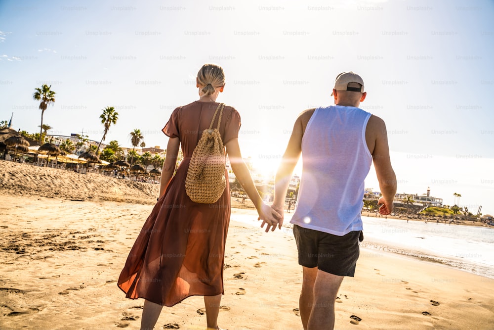 Couple on a walk on the tropical beach, Tenerife. Back view.