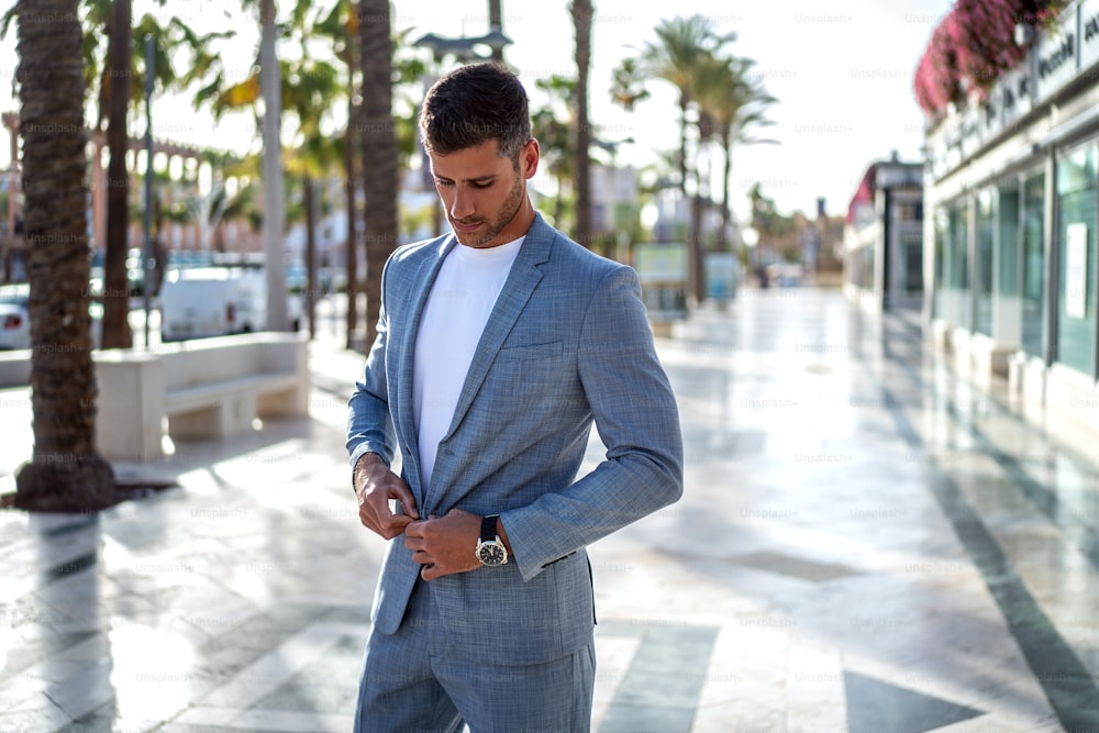 Hübscher italienischer Mann, der auf der Straße der Stadt geht und einen eleganten modischen Anzug trägt. Moderner Geschäftsmann.