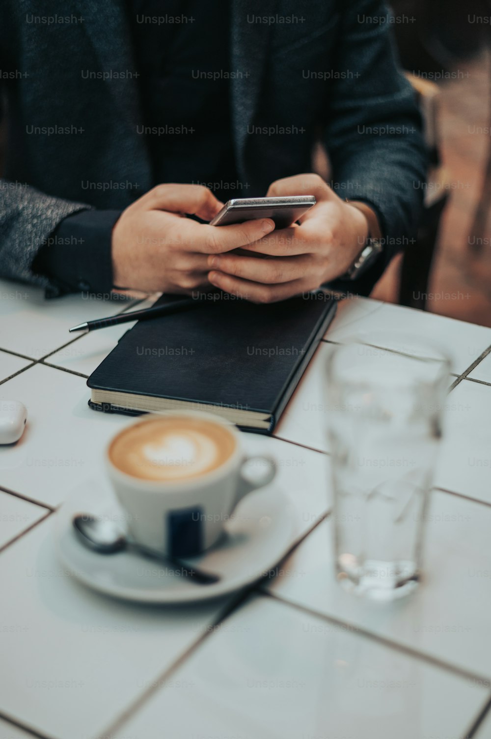 カフェで仕事をしながらコーヒーを飲みながらスマートフォンを使うビジネスマンの手