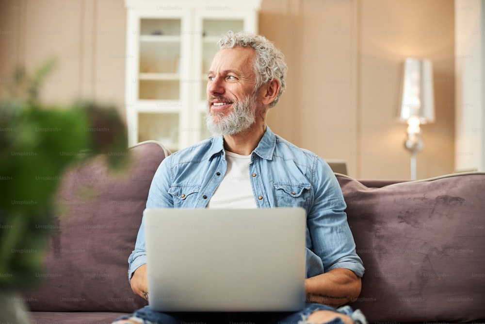 Handsome mature male expressing positivity while typing email to his partner