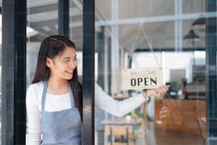 Small business owner smiling while turning the sign for the reopening of the place after the quarantine due to covid-19. Close up of womanÂÂ hands holding sign now we are open support local business.