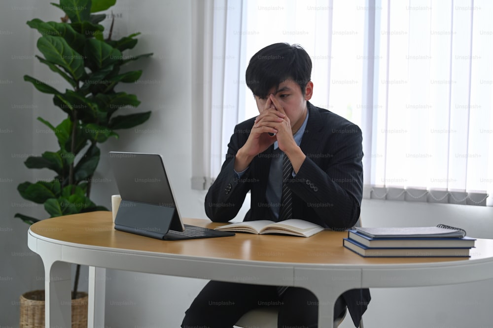 Hombre de negocios frustrado que se siente cansado y sufre por el trabajo mientras está sentado en la oficina.