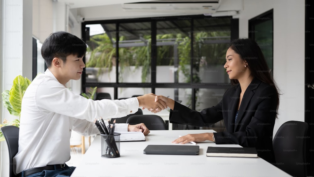 Businesspeople shaking hands during meeting in modern office for successful agreement.