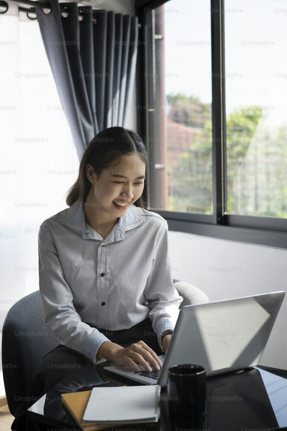 Portrait of smiling young woman employee working with laptop computer at office.