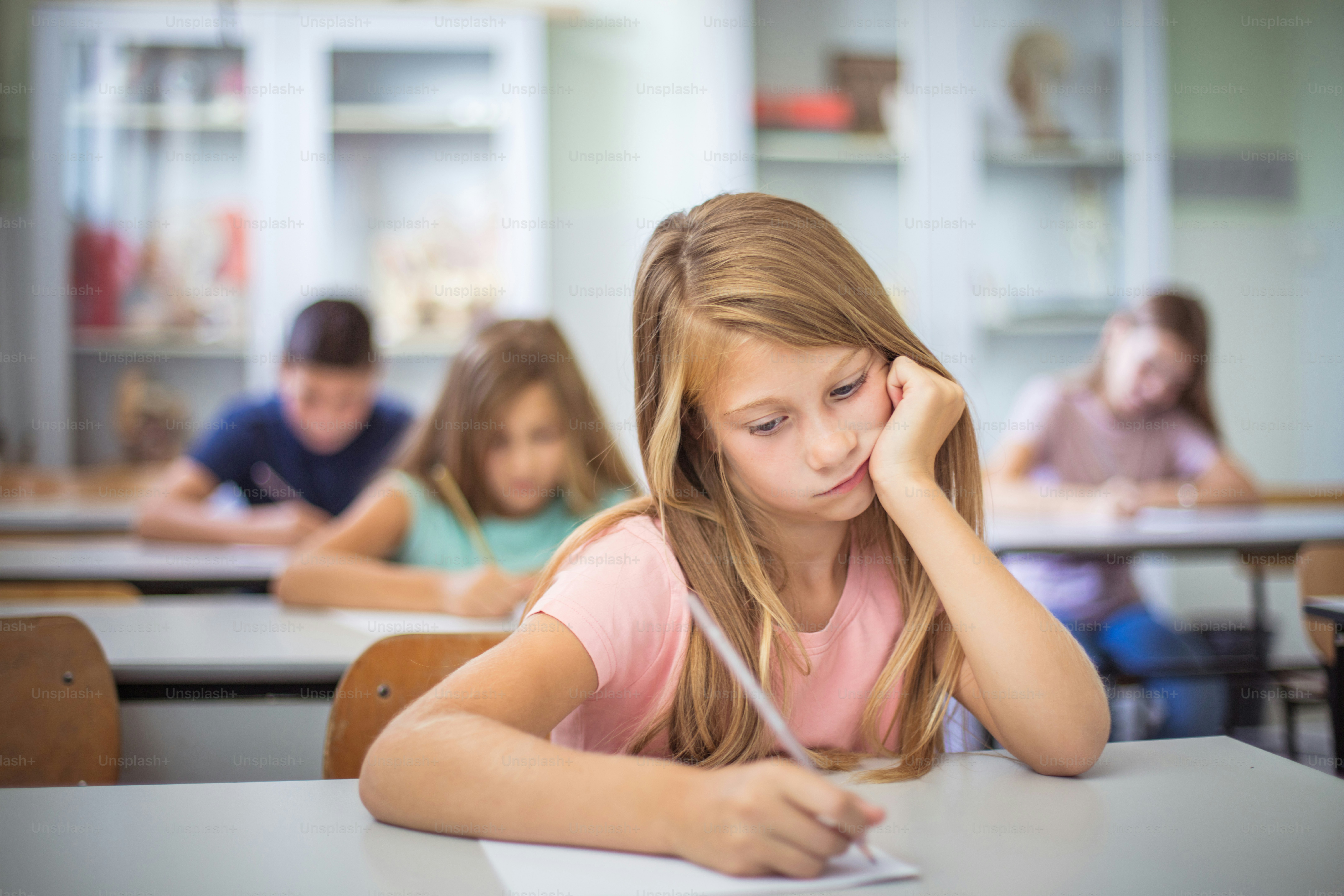 Taking a Test. Teenagers students sitting in the classroom. Focus is on foreground.