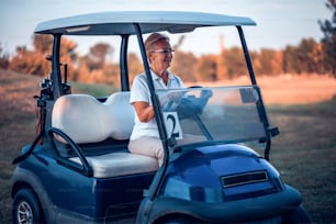 Femme âgée conduisant une voiture de golf.