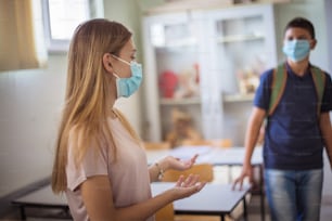 Die Maske ist auf dem Gesicht und soziale Distanz ist in der Schule vorhanden. Zwei Schulkinder mit Gesichtsmaske im Klassenzimmer.