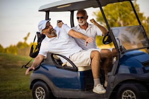 Two older friends are riding in a golf cart.