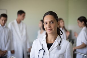 It's time for young doctors. Portrait of female doctor in hospital. Group of people in patient room.