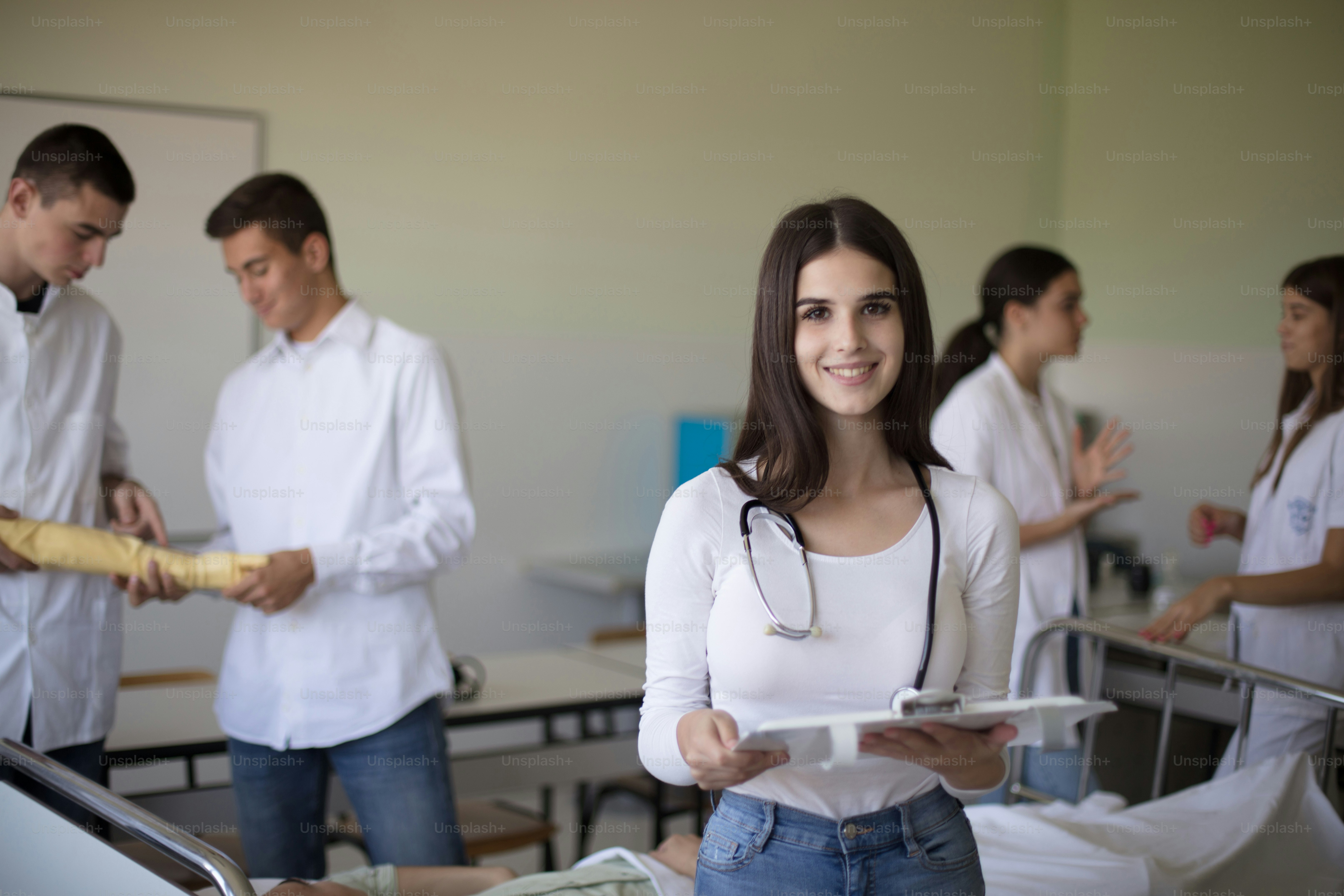 Young medical student. Medical students in patient's hospital room. Focus is on foreground. Looking at camera.